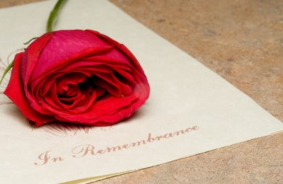 A funeral bulletin with a single red rose.